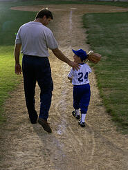 rear view of a man walking with his son at a playing field